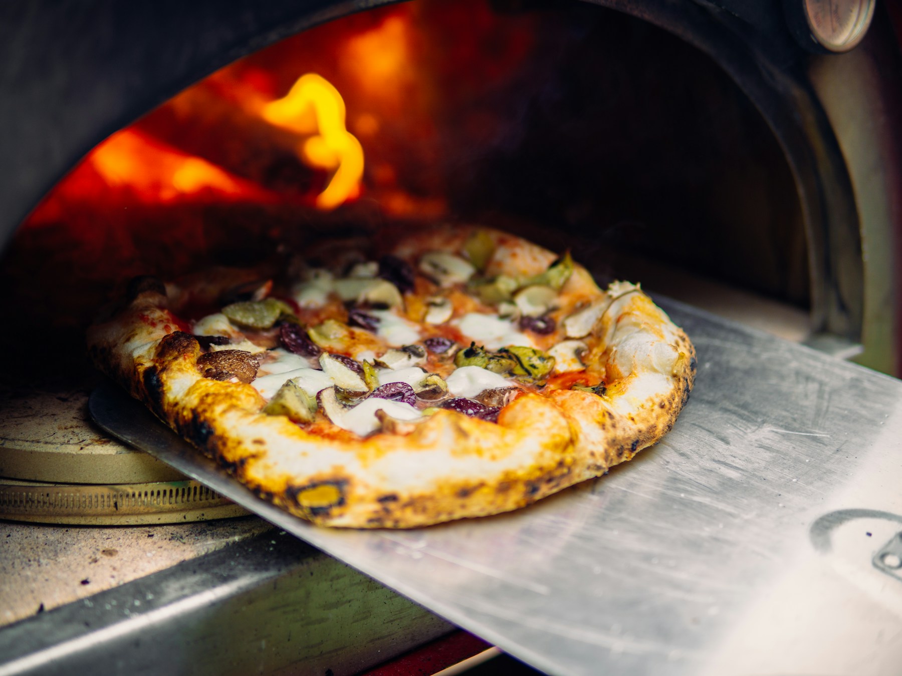 Pizza rustique retirée d’un four à bois, photographie d’ambiance